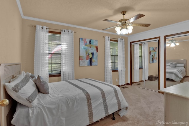 bedroom featuring ceiling fan, crown molding, light carpet, and two closets