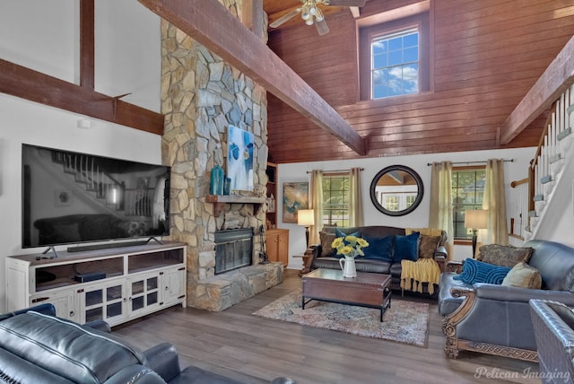 living room featuring ceiling fan, beam ceiling, wooden ceiling, a fireplace, and hardwood / wood-style floors