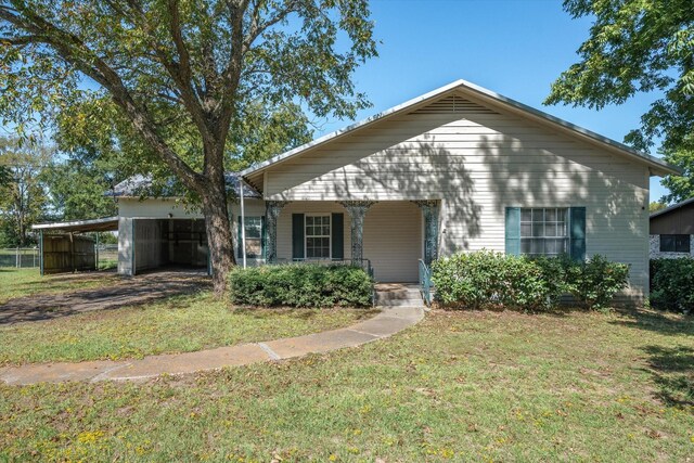 rear view of property with a carport and a yard