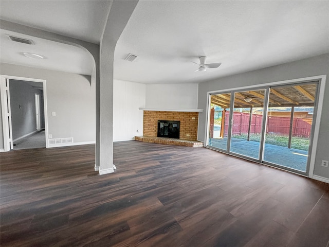 unfurnished living room featuring a fireplace, dark hardwood / wood-style floors, and ceiling fan