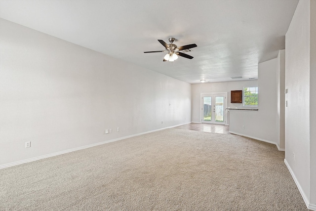 unfurnished living room featuring french doors, light colored carpet, and ceiling fan