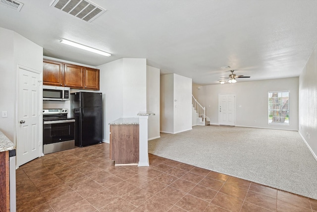 kitchen featuring light stone counters, ceiling fan, stainless steel appliances, carpet, and a textured ceiling