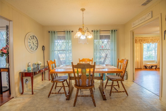 dining area with ornamental molding, a textured ceiling, and a notable chandelier