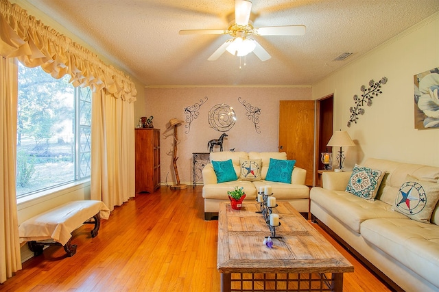 living room featuring ceiling fan, crown molding, hardwood / wood-style flooring, and a textured ceiling