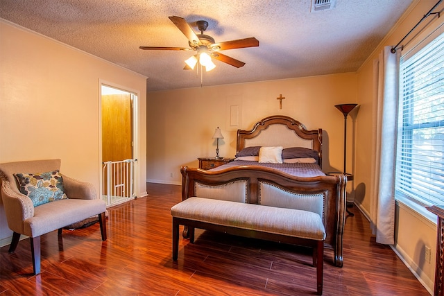 bedroom featuring ornamental molding, dark hardwood / wood-style flooring, a textured ceiling, and ceiling fan