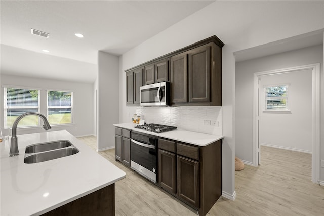 kitchen with a healthy amount of sunlight, appliances with stainless steel finishes, sink, and light wood-type flooring