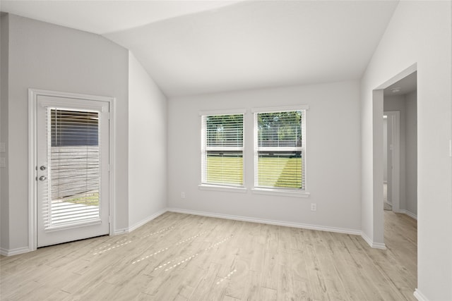 spare room with light hardwood / wood-style floors and vaulted ceiling