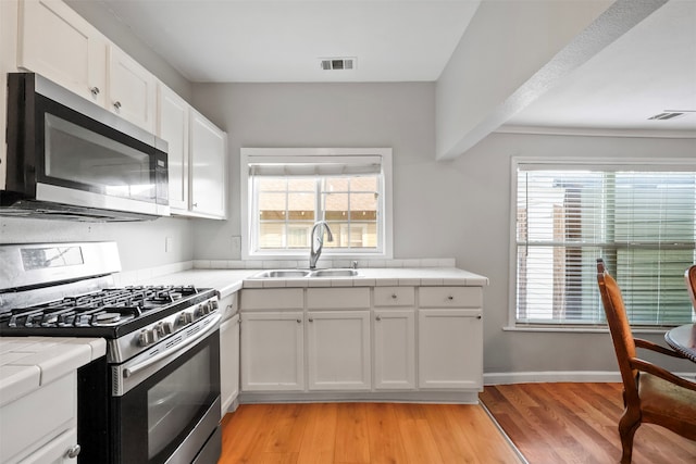 kitchen featuring a wealth of natural light, white cabinetry, sink, and stainless steel appliances