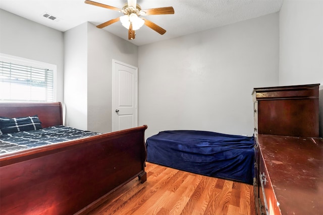 bedroom featuring ceiling fan, hardwood / wood-style floors, and a textured ceiling