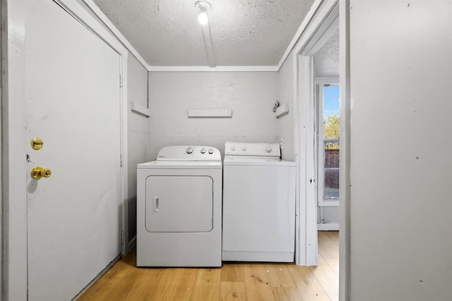 clothes washing area with independent washer and dryer, light hardwood / wood-style flooring, and a textured ceiling