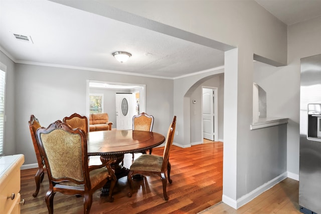 dining area with hardwood / wood-style flooring and crown molding