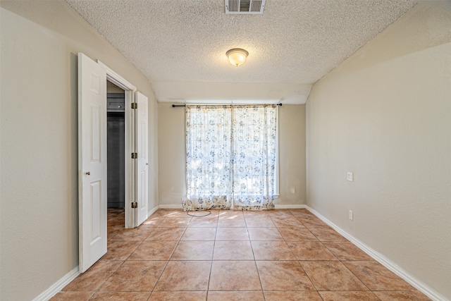 tiled empty room featuring a textured ceiling