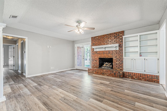 unfurnished living room featuring a textured ceiling, a fireplace, light hardwood / wood-style floors, and ceiling fan