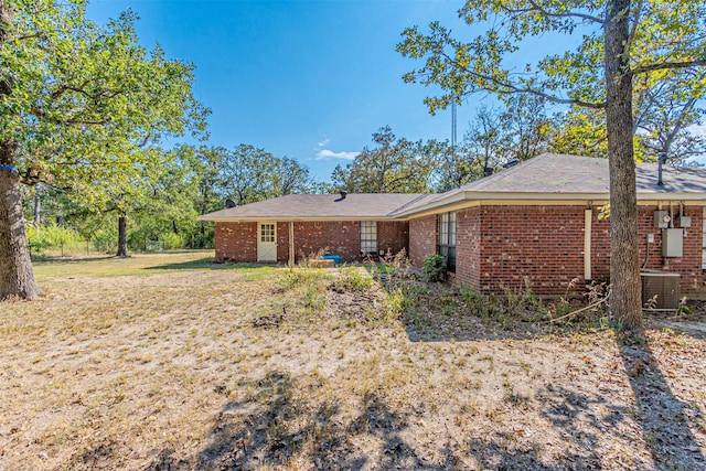 exterior space with brick siding, central AC, and a lawn