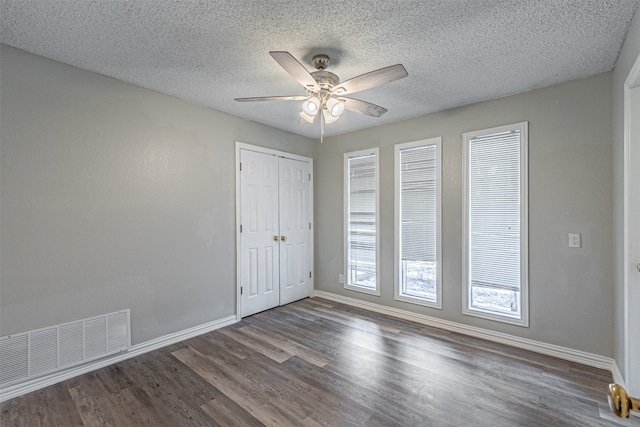 spare room with a textured ceiling, ceiling fan, and dark hardwood / wood-style flooring