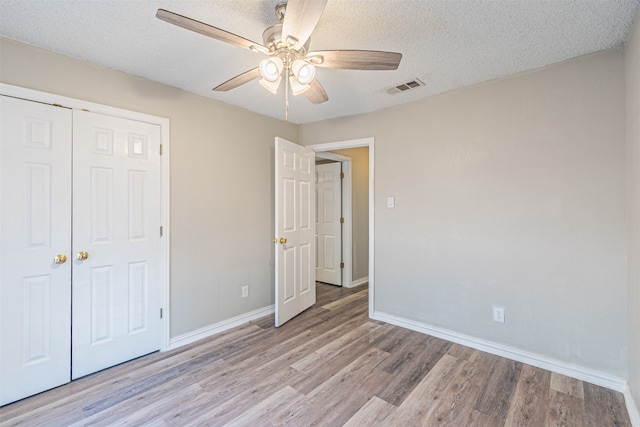 unfurnished bedroom with a closet, light hardwood / wood-style flooring, a textured ceiling, and ceiling fan