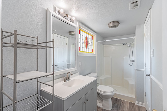 bathroom with vanity, wood-type flooring, a textured ceiling, a shower, and toilet