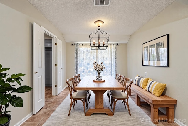 dining room featuring baseboards, visible vents, a notable chandelier, and a textured ceiling