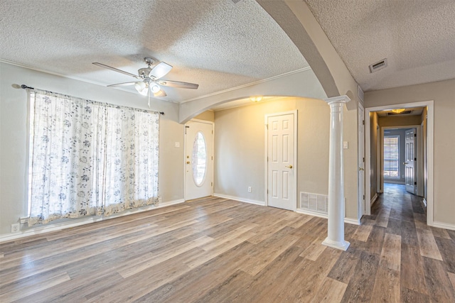 empty room with decorative columns, wood-type flooring, and ceiling fan