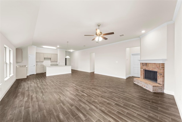 unfurnished living room featuring a brick fireplace, crown molding, dark wood-type flooring, and ceiling fan