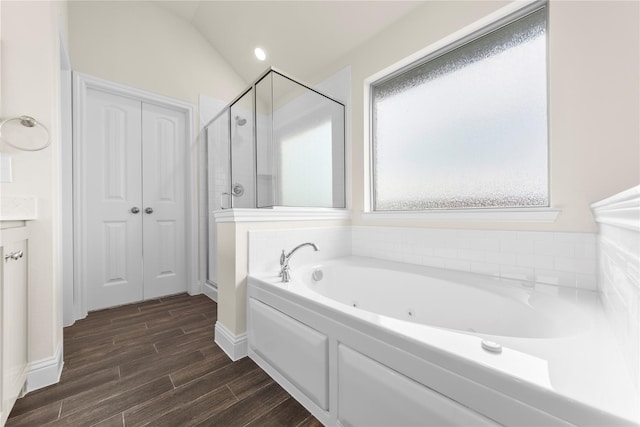 bathroom with lofted ceiling, hardwood / wood-style flooring, and plus walk in shower