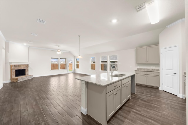 kitchen with sink, dark hardwood / wood-style flooring, a fireplace, vaulted ceiling, and gray cabinets