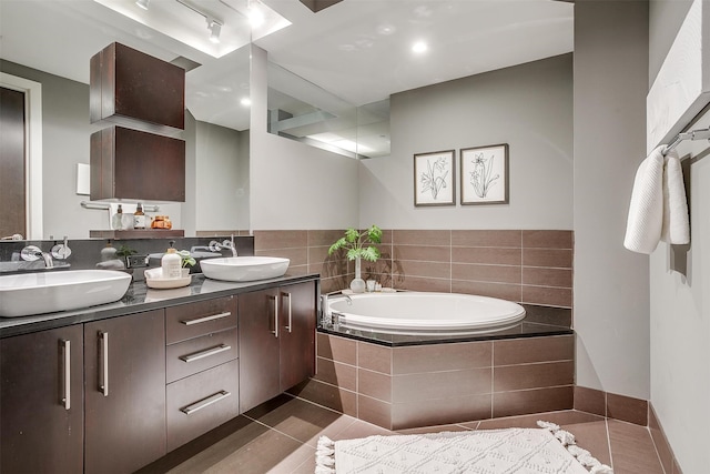 bathroom featuring tile patterned floors, vanity, and tiled bath