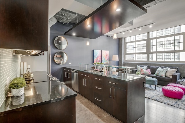 kitchen featuring dark brown cabinets, dark stone countertops, sink, an island with sink, and stainless steel dishwasher