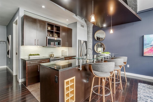 kitchen with dark brown cabinetry, a breakfast bar, dark hardwood / wood-style floors, hanging light fixtures, and appliances with stainless steel finishes