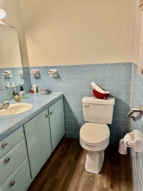 bathroom with wood-type flooring, vanity, tile walls, and toilet