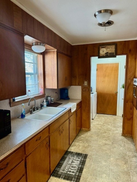 kitchen with separate washer and dryer, backsplash, wood walls, and sink