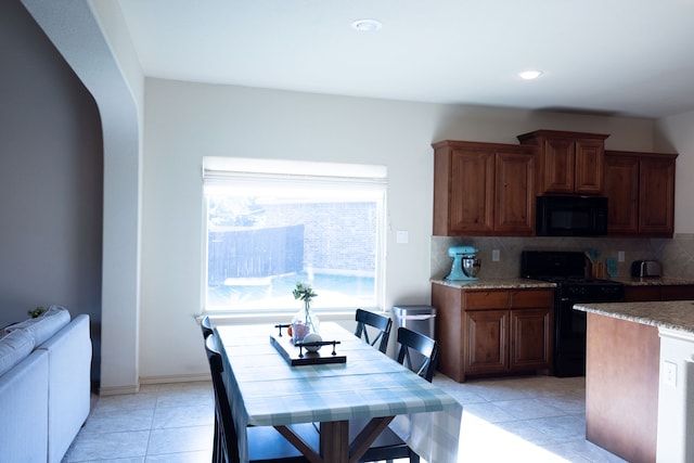 kitchen featuring black appliances, light tile patterned floors, and backsplash