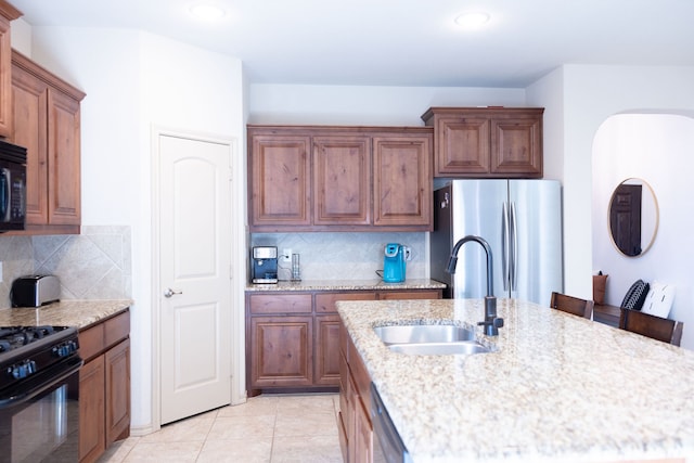 kitchen with tasteful backsplash, black appliances, sink, and a breakfast bar