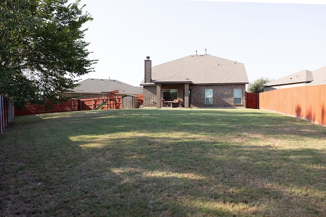 back of property featuring a playground and a lawn