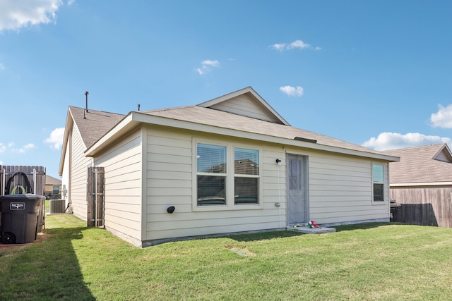 rear view of house featuring central AC unit and a lawn