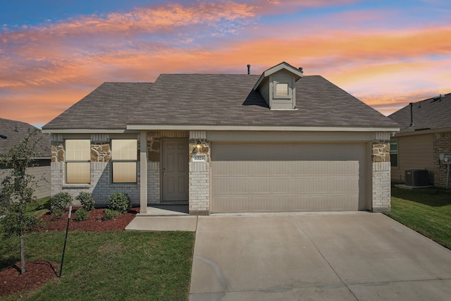 view of front of house featuring a garage, a yard, and central air condition unit