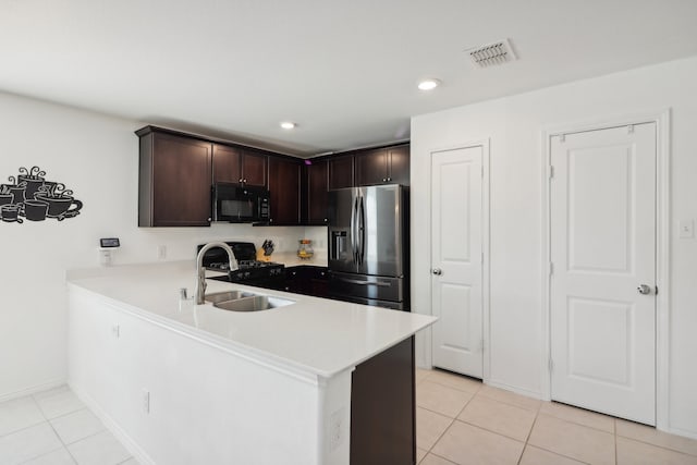 kitchen with dark brown cabinetry, light tile patterned floors, sink, kitchen peninsula, and black appliances