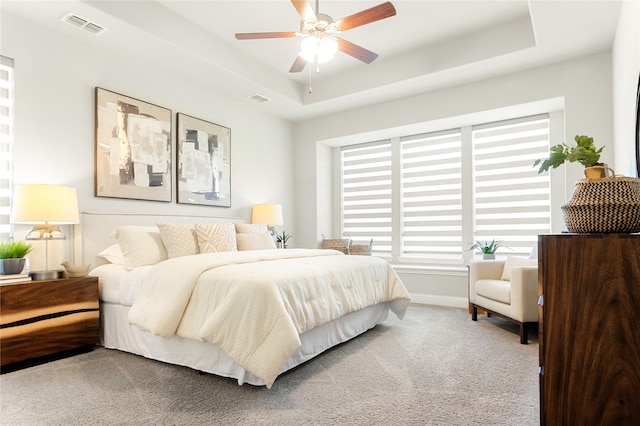 carpeted bedroom featuring ceiling fan and a raised ceiling