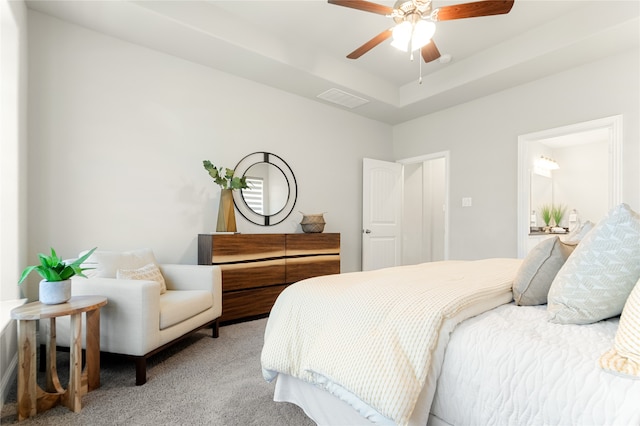 carpeted bedroom with ceiling fan and a raised ceiling