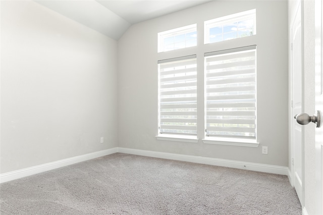 unfurnished room with lofted ceiling, plenty of natural light, and carpet floors