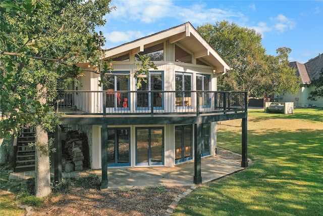 back of property featuring a wooden deck, a yard, and a patio