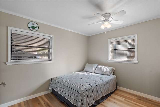 bedroom with ornamental molding, multiple windows, ceiling fan, and light hardwood / wood-style flooring