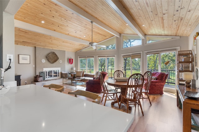 dining space with hardwood / wood-style floors, a large fireplace, ceiling fan, and wooden ceiling