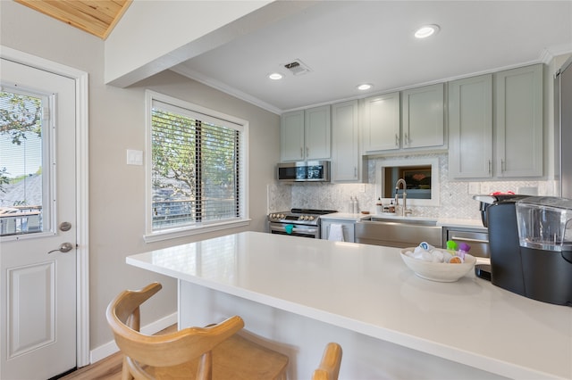 kitchen featuring decorative backsplash, a breakfast bar, sink, kitchen peninsula, and appliances with stainless steel finishes