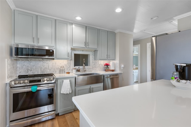 kitchen featuring ornamental molding, sink, light hardwood / wood-style flooring, stainless steel appliances, and decorative backsplash