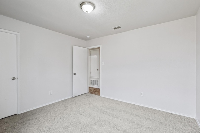 empty room with light carpet and a textured ceiling