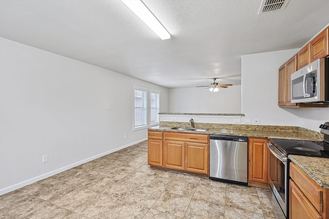 kitchen featuring ceiling fan, sink, stone countertops, a textured ceiling, and appliances with stainless steel finishes