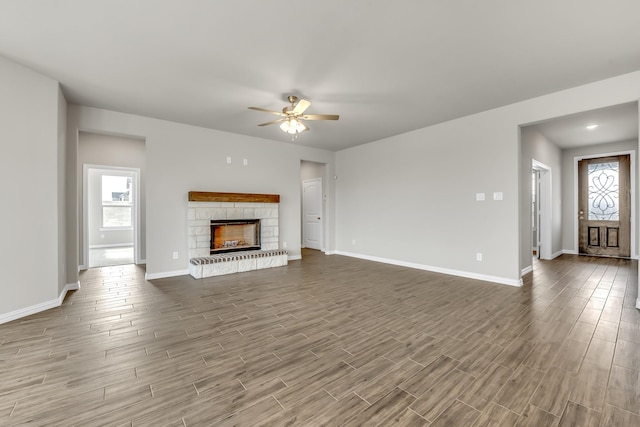 unfurnished living room with ceiling fan, plenty of natural light, and a stone fireplace