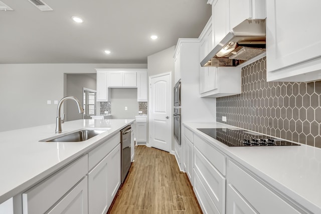 kitchen with exhaust hood, stainless steel appliances, light wood-type flooring, white cabinets, and sink