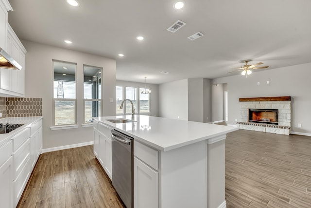 kitchen with sink, white cabinetry, dishwasher, and an island with sink